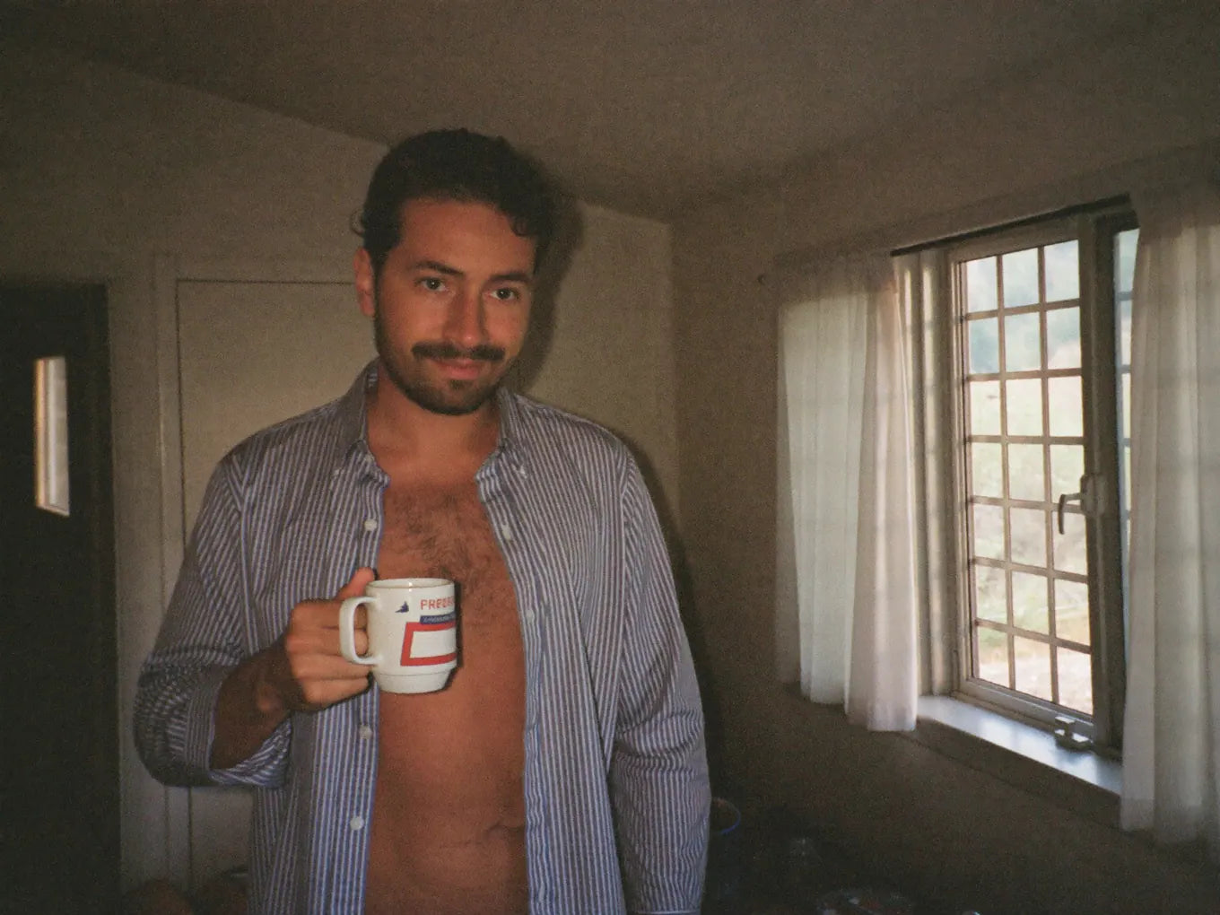 UGC — energized man in kitchen at sunrise, holding mug, looking genuinely awake