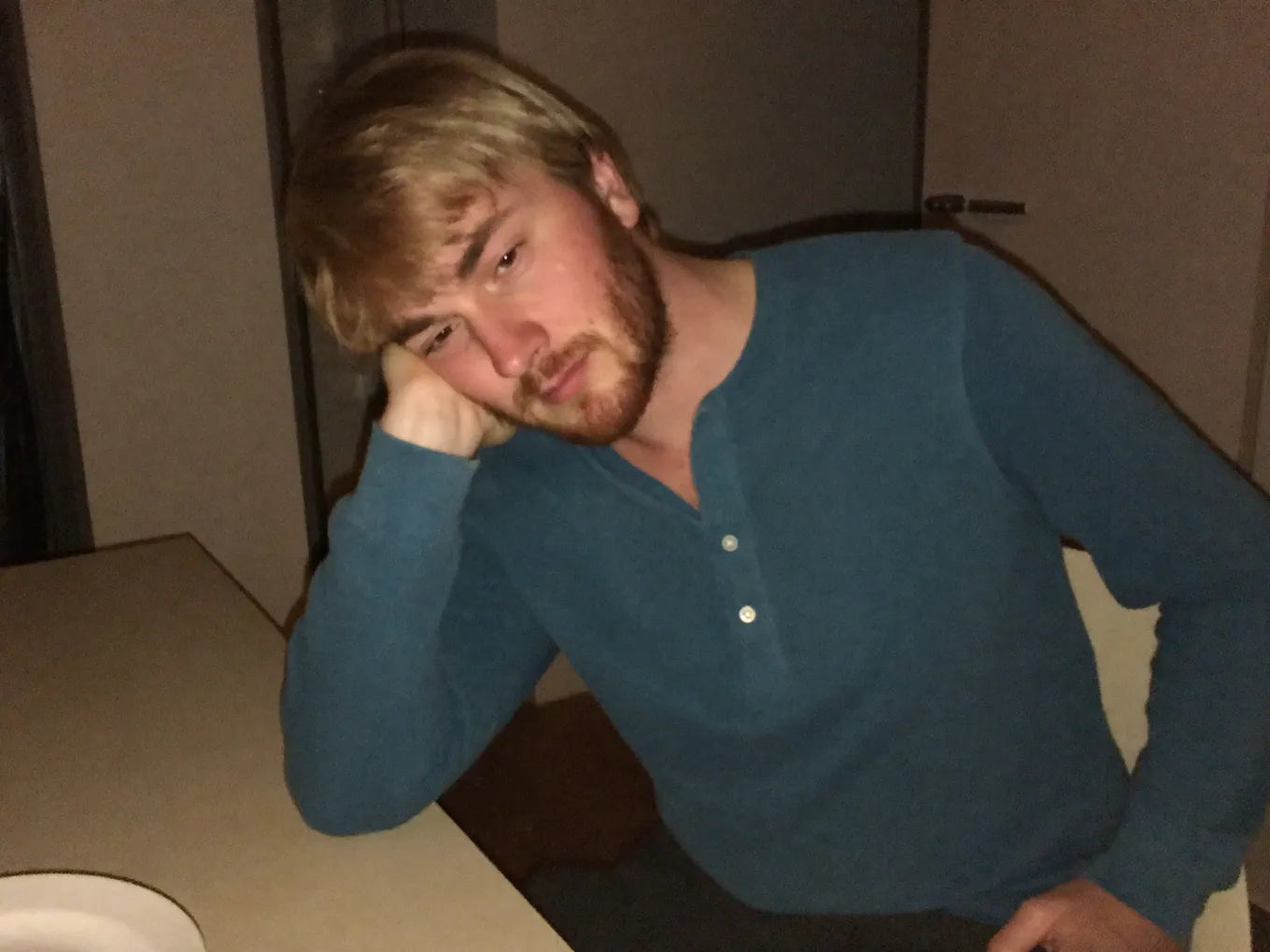 UGC PHONE PHOTO — tired dad slumped at kitchen table in work clothes, evening, kids in background blurred