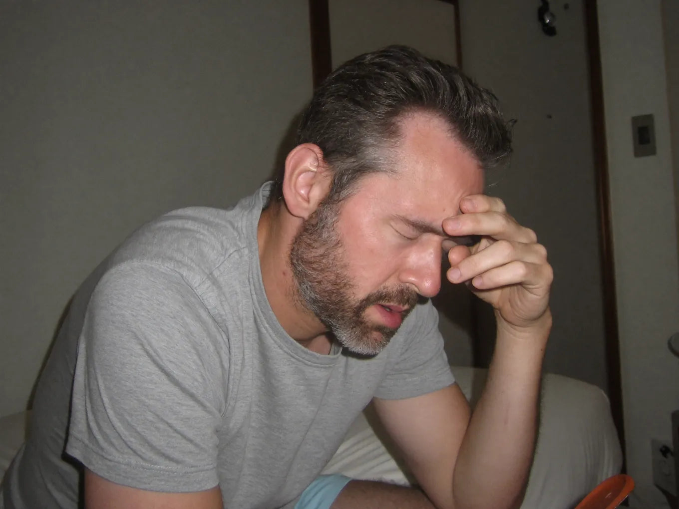 Tired man sitting on the edge of his bed in the morning
